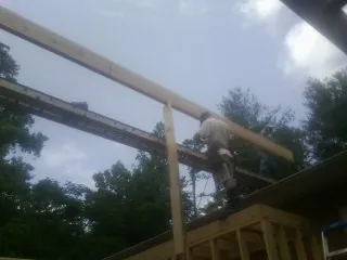 Carpenter setting a ridge beam over a new addition frame — Ice Dam Removal by Roofing Brothers in Patchogue