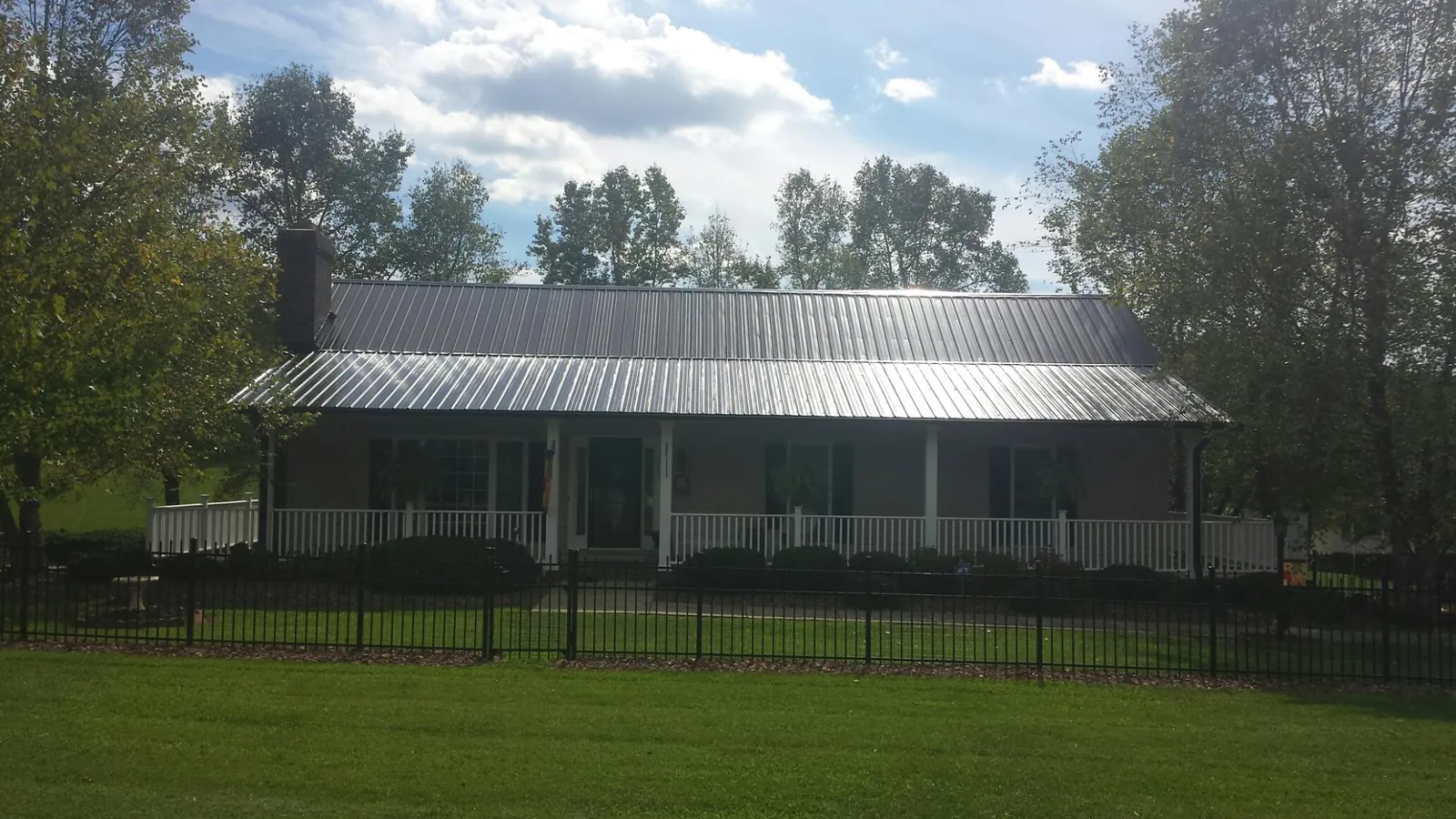 Gray metal roof on a brick ranch with a full width front porch — Gutter Guard Installation work by our crew in Patchogue