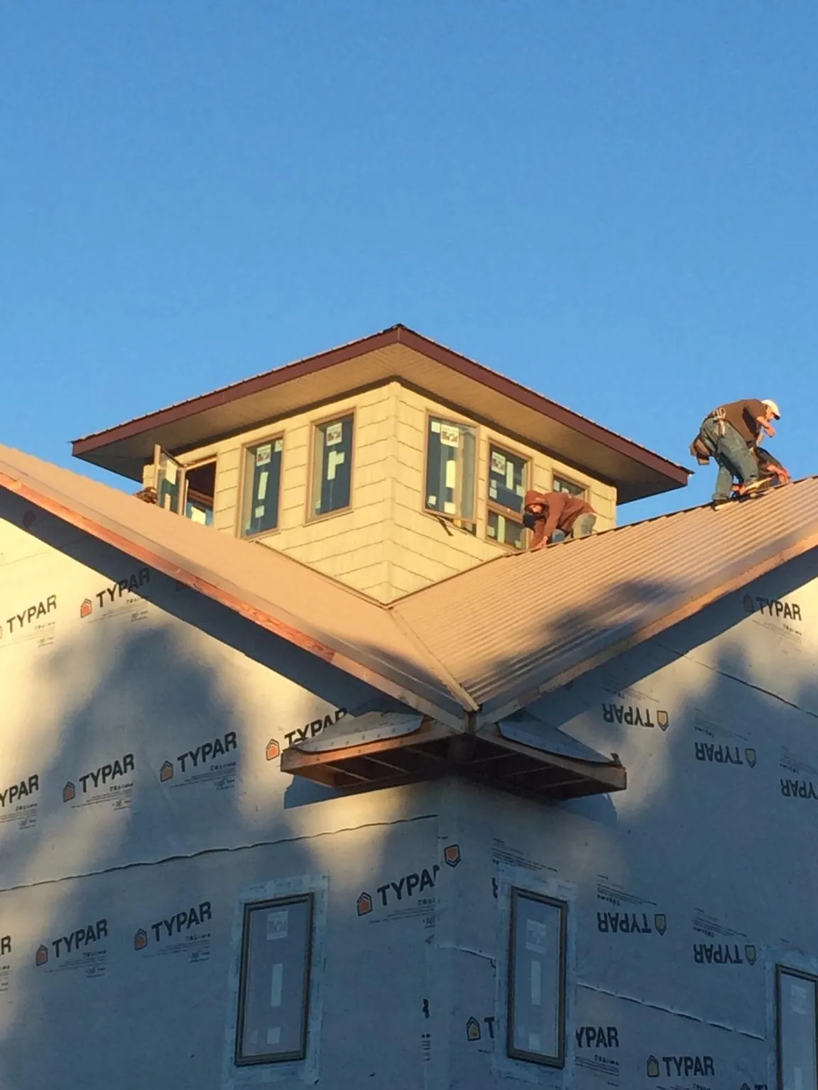 Roofers working around a rooftop cupola on a new metal roof at sunset — Roof Waterproofing in Patchogue by Roofing Brothers